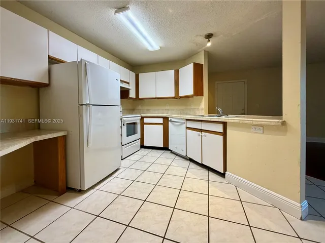 a kitchen with a sink a refrigerator and cabinets