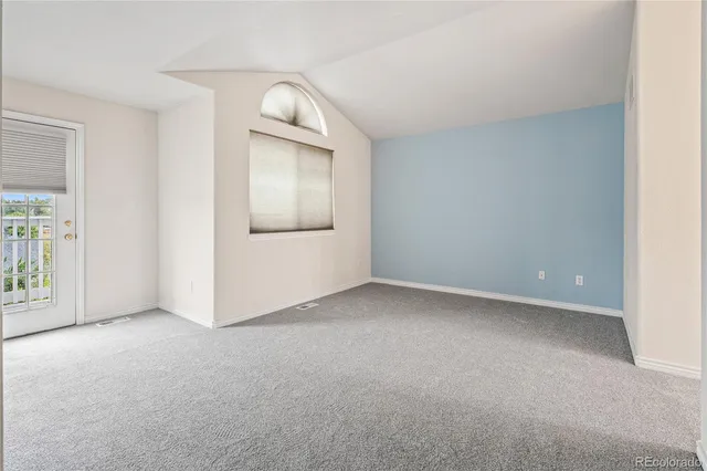 an empty room with windows and refrigerator