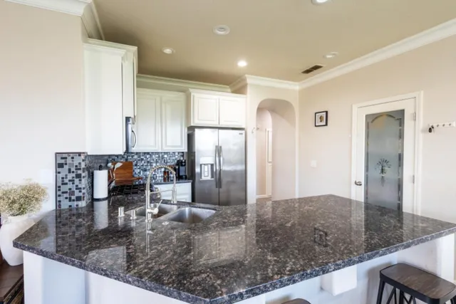 a kitchen with kitchen island granite countertop a sink a refrigerator and a counter top space