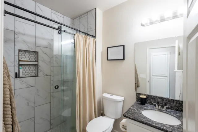 a bathroom with a granite countertop sink toilet a mirror and shower