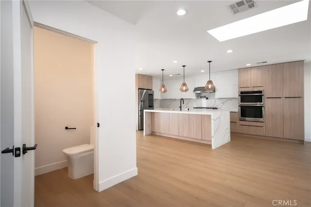 a large white kitchen with a stove a sink dishwasher and a refrigerator with wooden floor