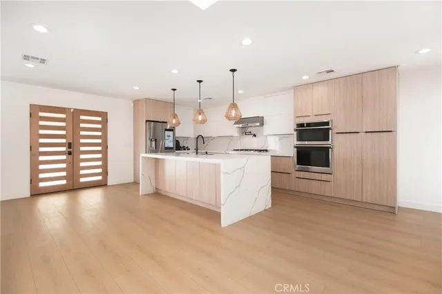 a large white kitchen with a stove a sink dishwasher and a refrigerator with wooden floor