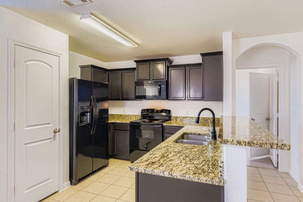 232 Millers Loop Jarrell, TX 76537 - Photo 11 of 34 a kitchen with a refrigerator and a sink