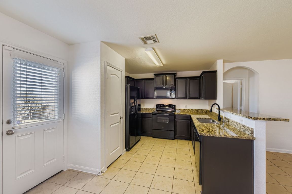 232 Millers Loop Jarrell, TX 76537 - Photo 13 of 34 a kitchen with granite countertop a refrigerator stove and sink