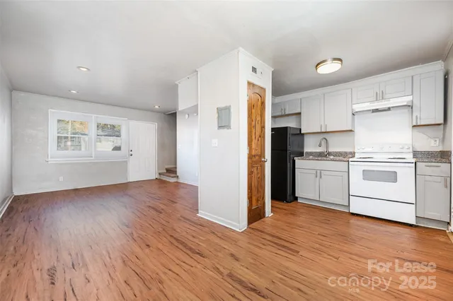 a kitchen with white cabinets and wooden floor