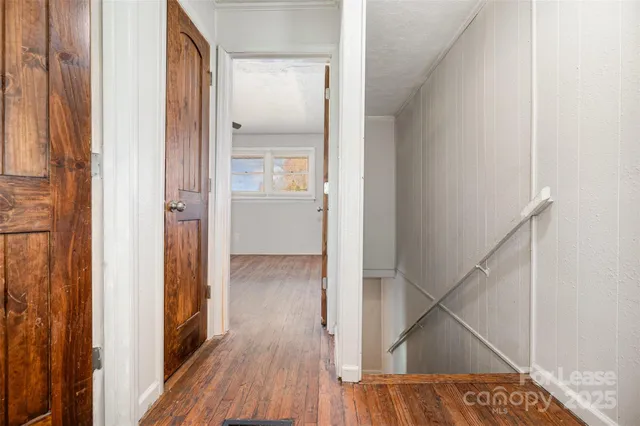 a view of a hallway with wooden floor and staircase