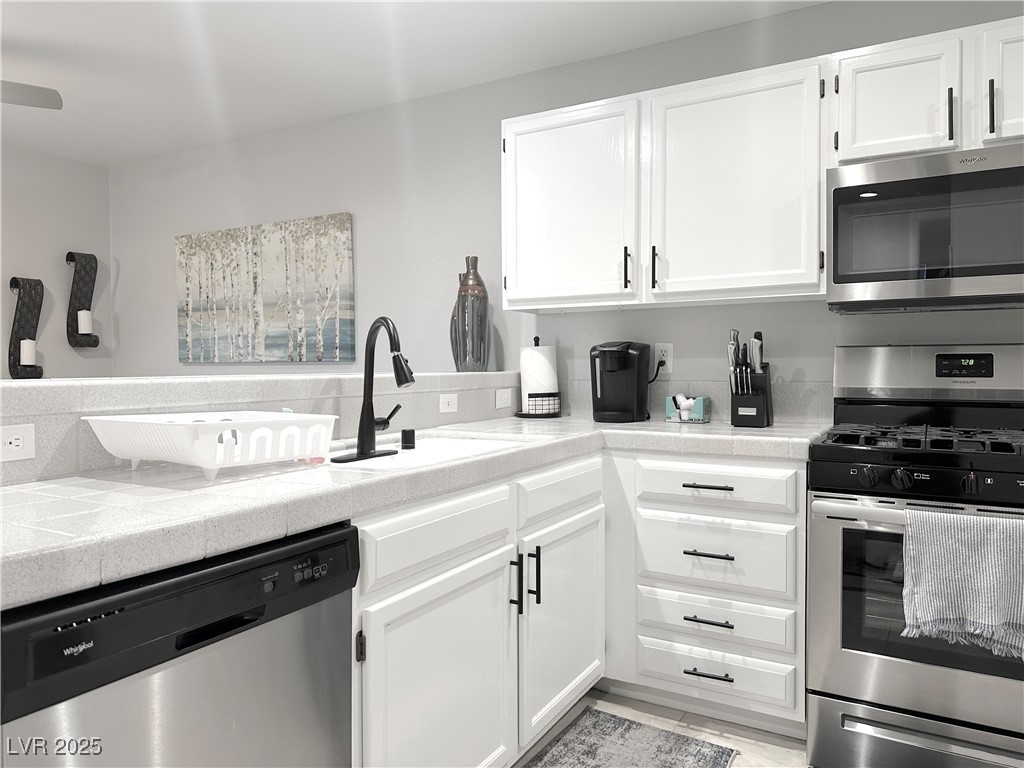 7950 West Flamingo Road, Unit 1173 Las Vegas, NV 89147 - Photo 13 of 31 Kitchen featuring white cabinets, a sink, appliances with stainless steel finishes, light countertops, and backsplash