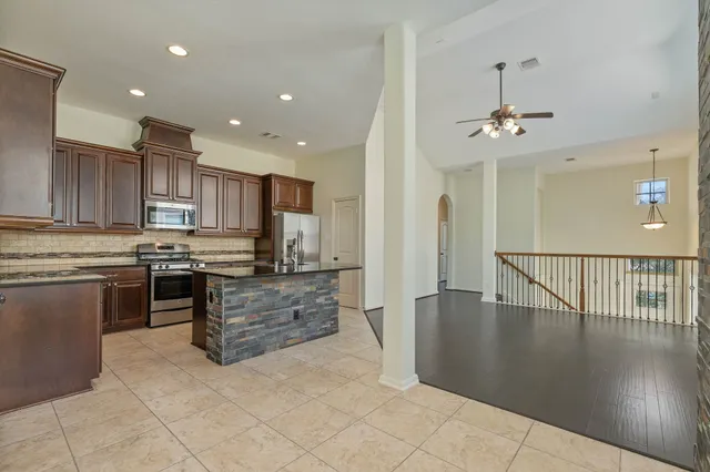 a large kitchen with stainless steel appliances kitchen island granite countertop a stove a refrigerator a sink and a oven