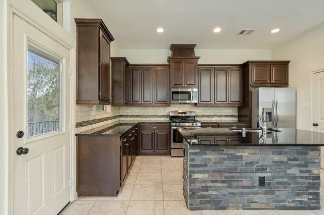 a kitchen with stainless steel appliances granite countertop a stove a sink and a microwave