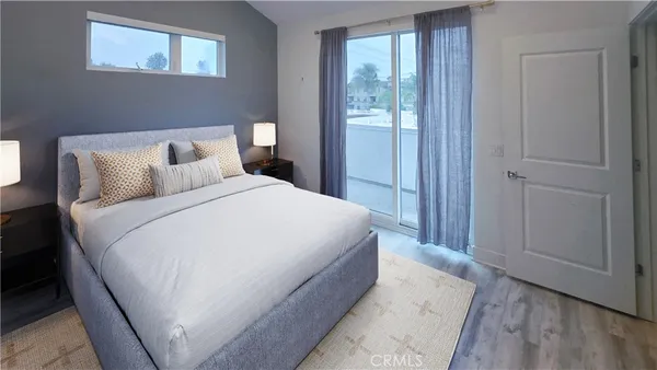 a large bed in a bedroom next to a window and a wooden floor