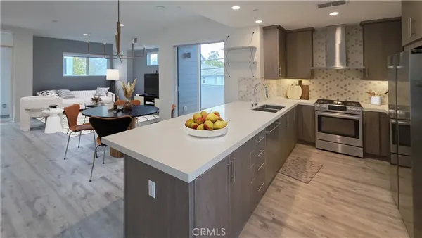 a kitchen with stainless steel appliances granite countertop a stove a sink dishwasher and a refrigerator with wooden floor