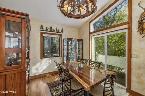 a view of a dining room with furniture large windows wooden floor and a chandelier