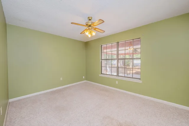 an empty room with a window and a fan