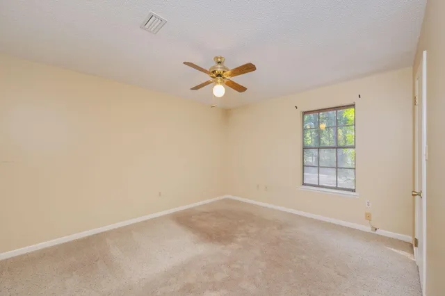 an empty room with a window and a fan
