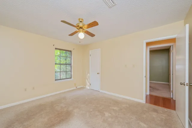 an empty room with windows and fan