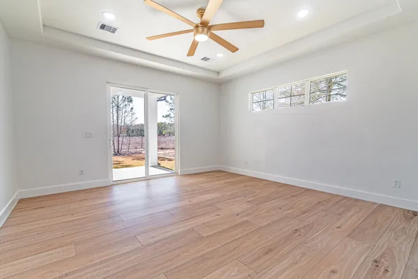 an empty room with wooden floor fan and windows