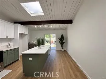 a room with kitchen island a sink wooden floor and glass door