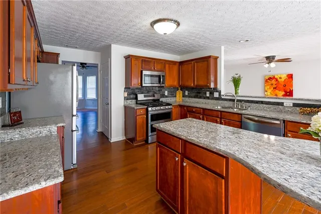 a kitchen with stainless steel appliances granite countertop sink stove top oven and cabinets