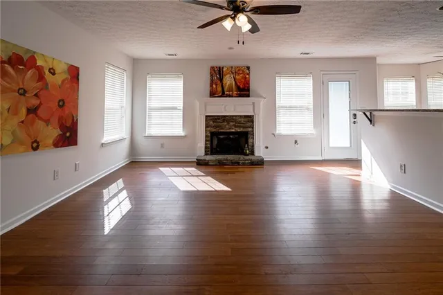 a view of a livingroom with wooden floor a ceiling fan and windows