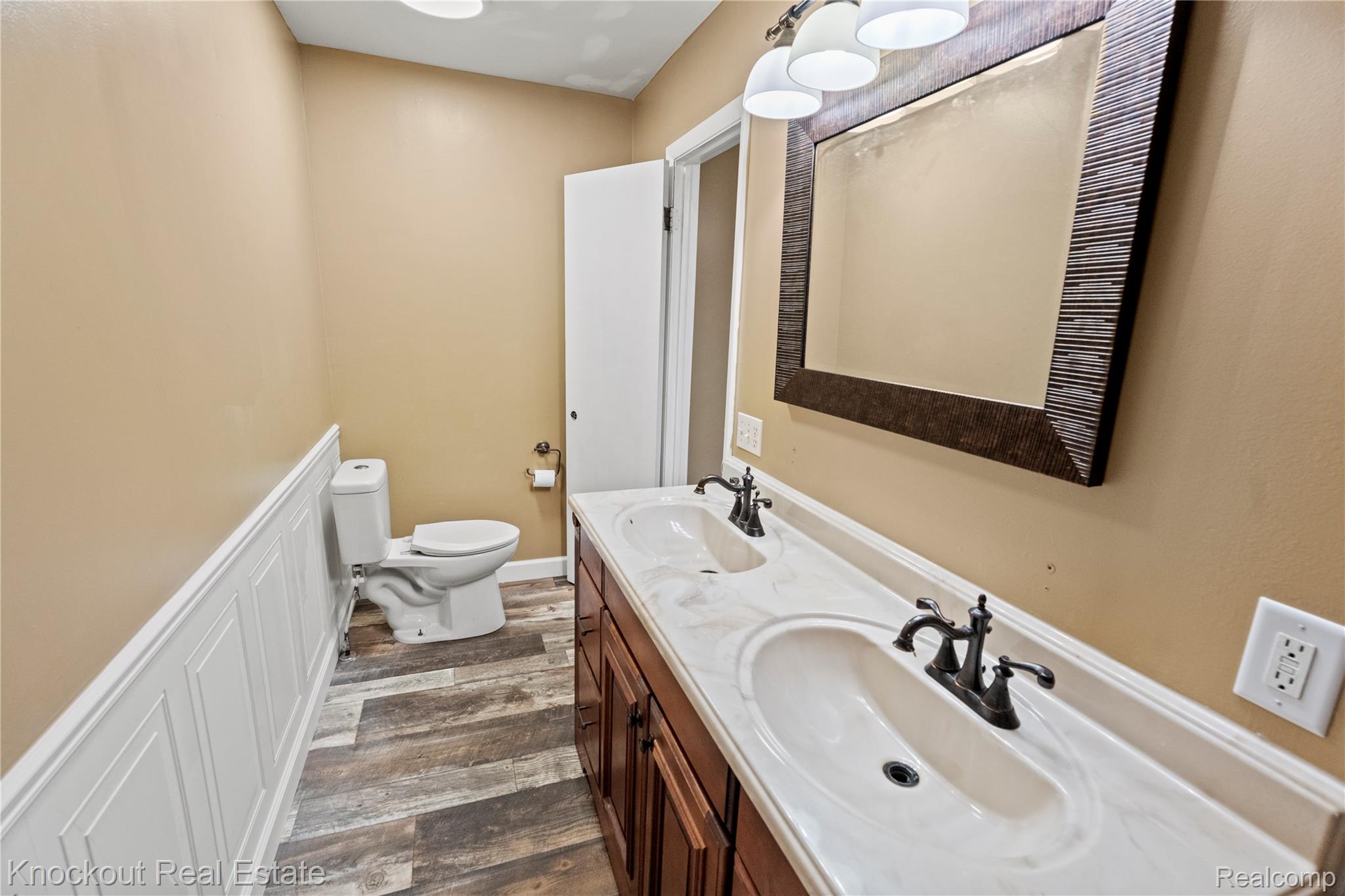 5750 Maple Road Frankenmuth, MI 48734 - Photo 30 of 60 Bathroom featuring a dual vanity with integrated sinks, wood-finish cabinetry, and dark bronze fixtures