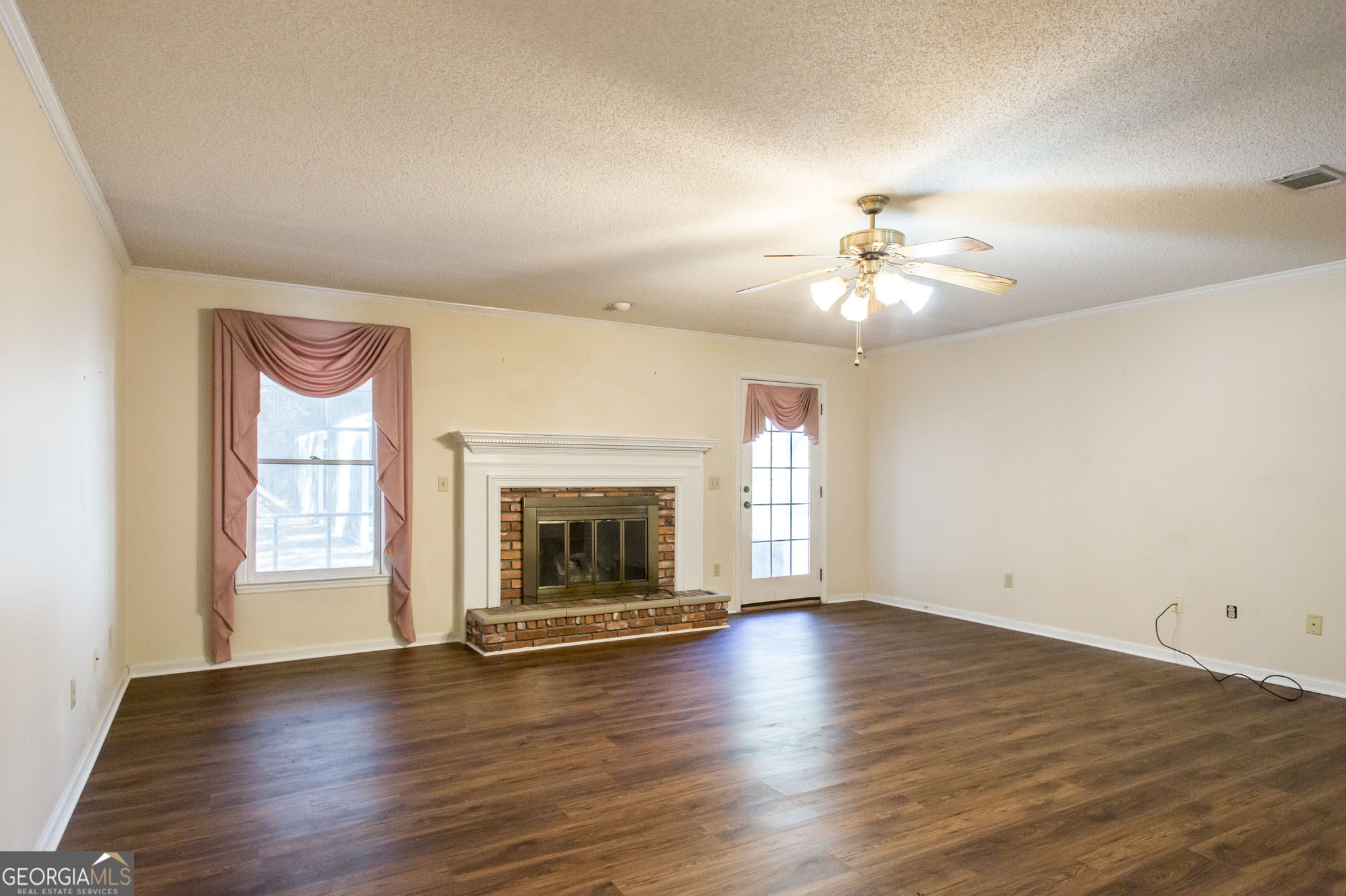 2959 Chadwick Drive Waycross, GA 31501 - Photo 17 of 52 an empty room with wooden floor fireplace and windows