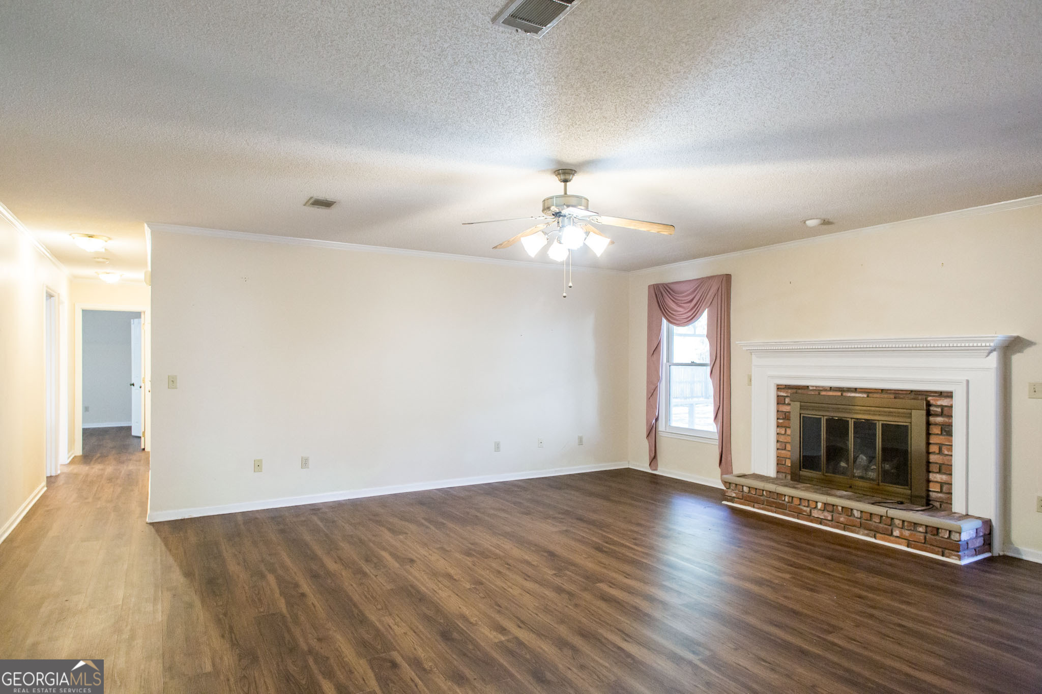 2959 Chadwick Drive Waycross, GA 31501 - Photo 25 of 52 an empty room with wooden floor fireplace and windows