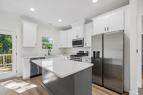 a kitchen with a sink cabinets wooden floor and stainless steel appliances