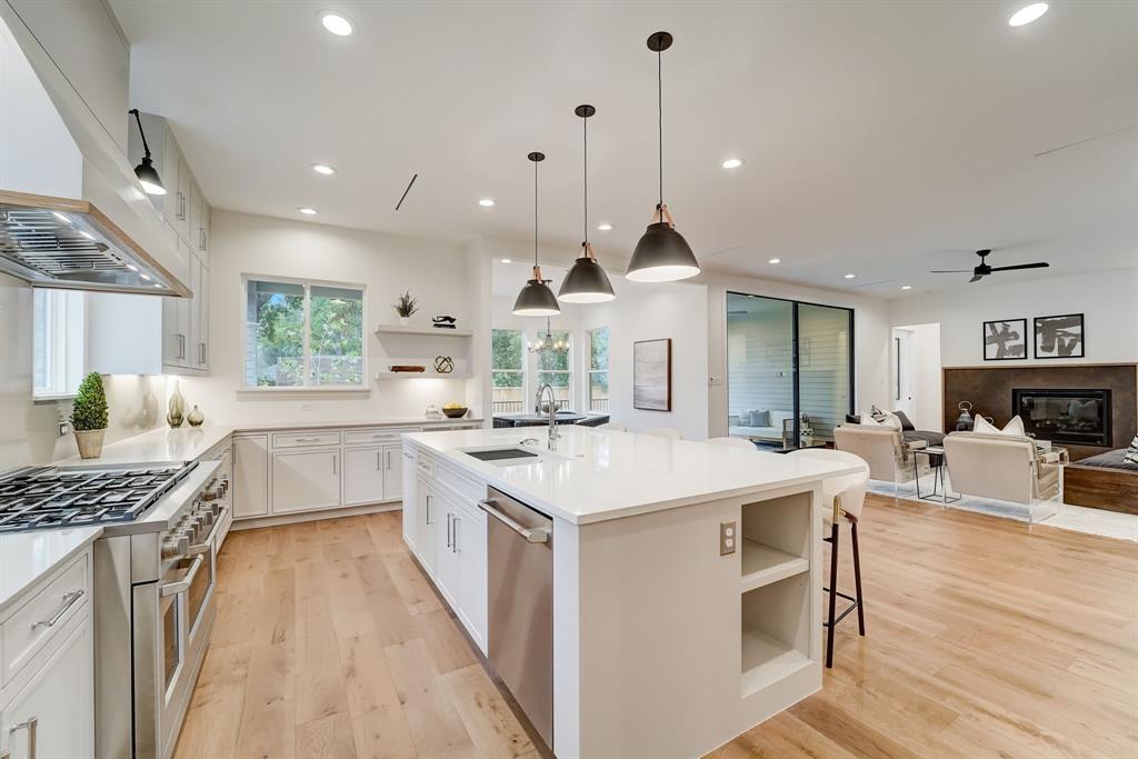 a large kitchen with kitchen island a stove a sink a center island and a wooden floor