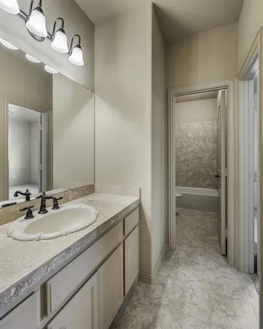 an empty room with a bathroom and a ceiling fan mirror