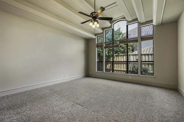 an empty room with windows and ceiling fan