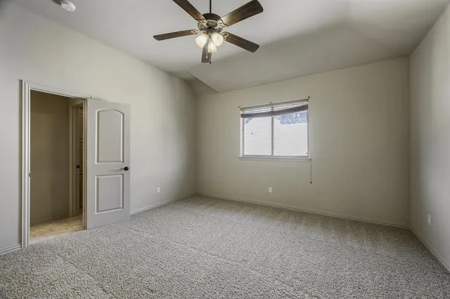 an empty room with chandelier fan and windows