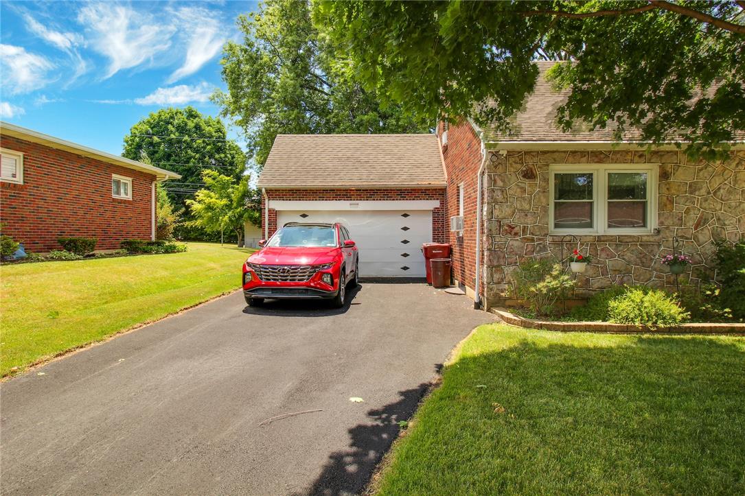 1256 Ridge Avenue Whitehall, PA 18052 - Photo 4 of 43 A well-maintained paved driveway leads to a single-door garage, set against a stone and brick facade.