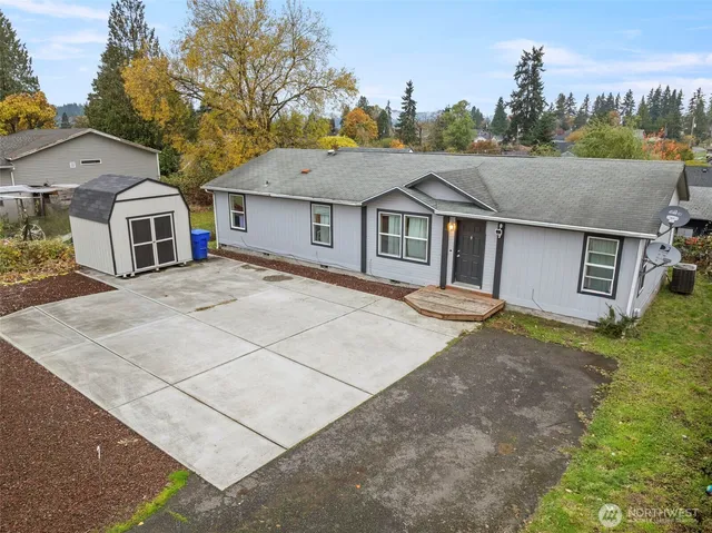a view of a white house next to a yard with large trees