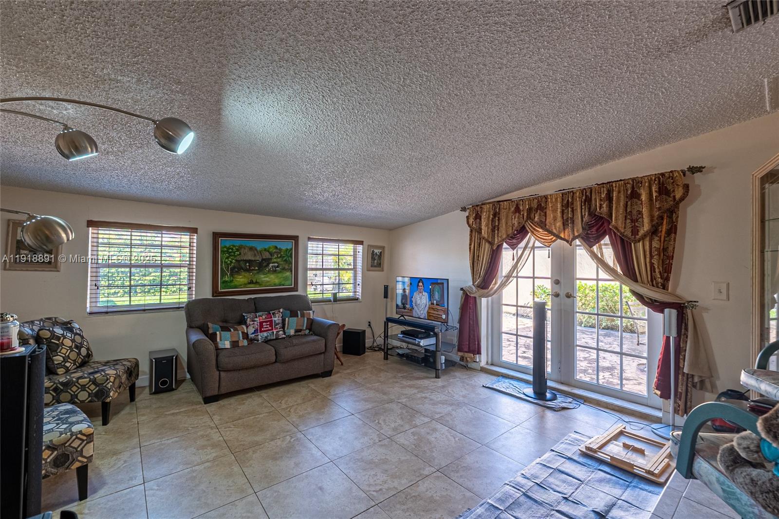 12421 Southwest 193rd Street Miami, FL 33177 - Photo 22 of 23 a living room with furniture a flat screen tv and a floor to ceiling window