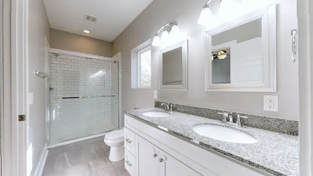 a bathroom with a granite countertop double vanity sink mirror and toilet