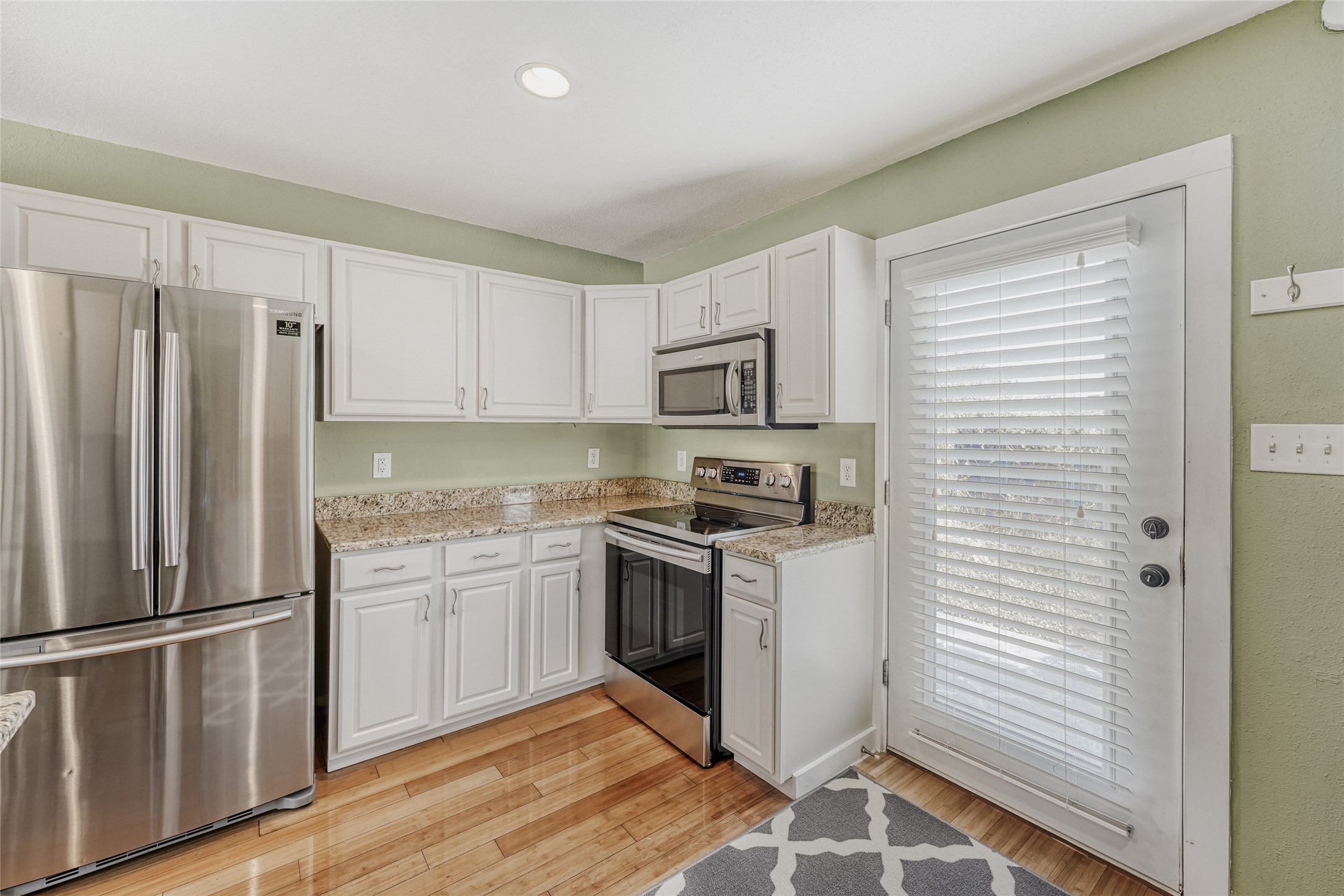 2000 Lightsey Road, Unit 3 Austin, TX 78704 - Photo 7 of 28 Kitchen with stainless steel appliances, white cabinets, light stone counters, and light wood-type flooring