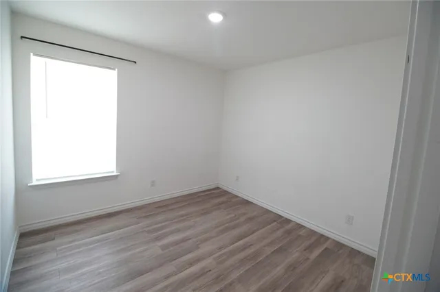 an empty room with wooden floor and window