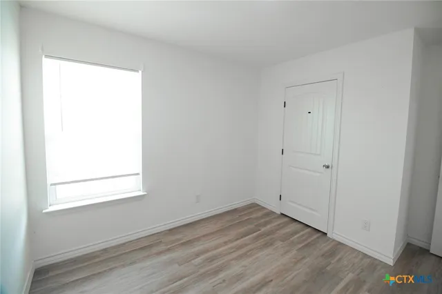 an empty room with wooden floor and window