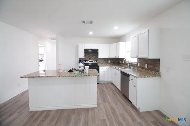 a kitchen with granite countertop a sink cabinets and wooden floor