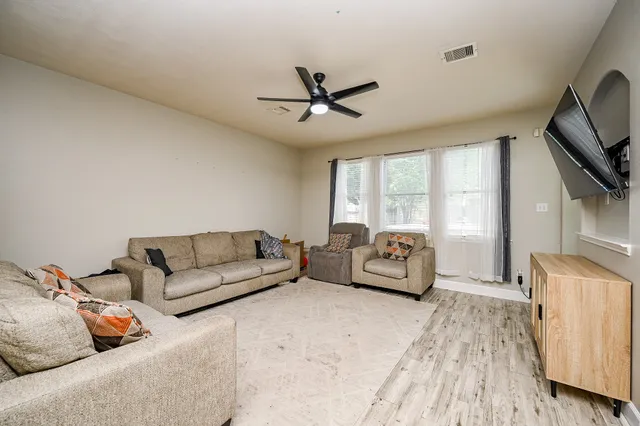a living room with furniture a ceiling fan and a flat screen tv