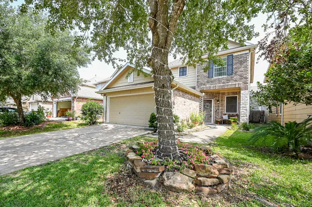 a view of a house with a yard and large tree
