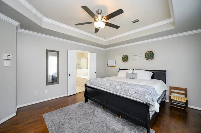 a bedroom with a bed and a large window with wooden floor