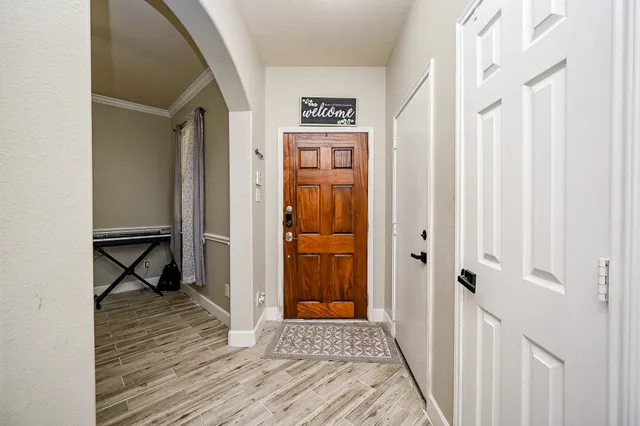 a view of a hallway with wooden floor and a bathroom