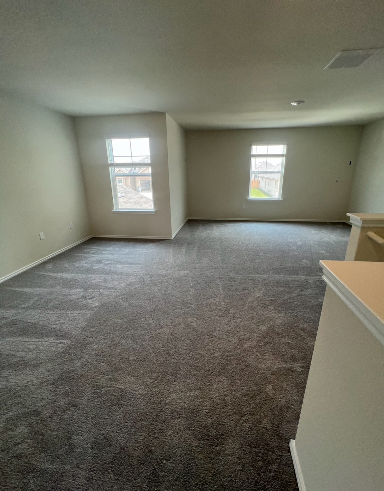 499 Tree Nut Loop Buda, TX 78610 - Photo 12 of 33 A spacious game room features soft carpeting and natural light from multiple windows.