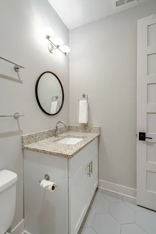 a bathroom with a granite countertop sink a toilet and a mirror