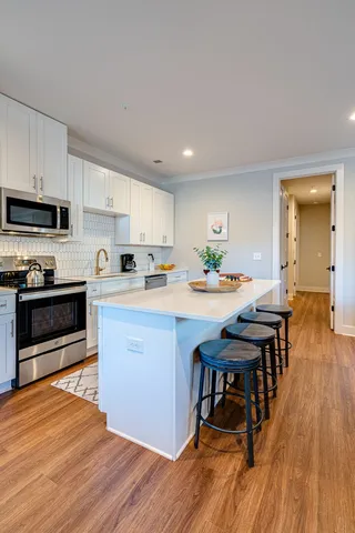 a kitchen with stainless steel appliances kitchen island granite countertop a table chairs sink and cabinets