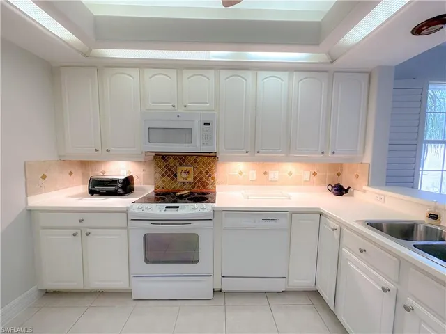 a kitchen with white cabinets and white appliances