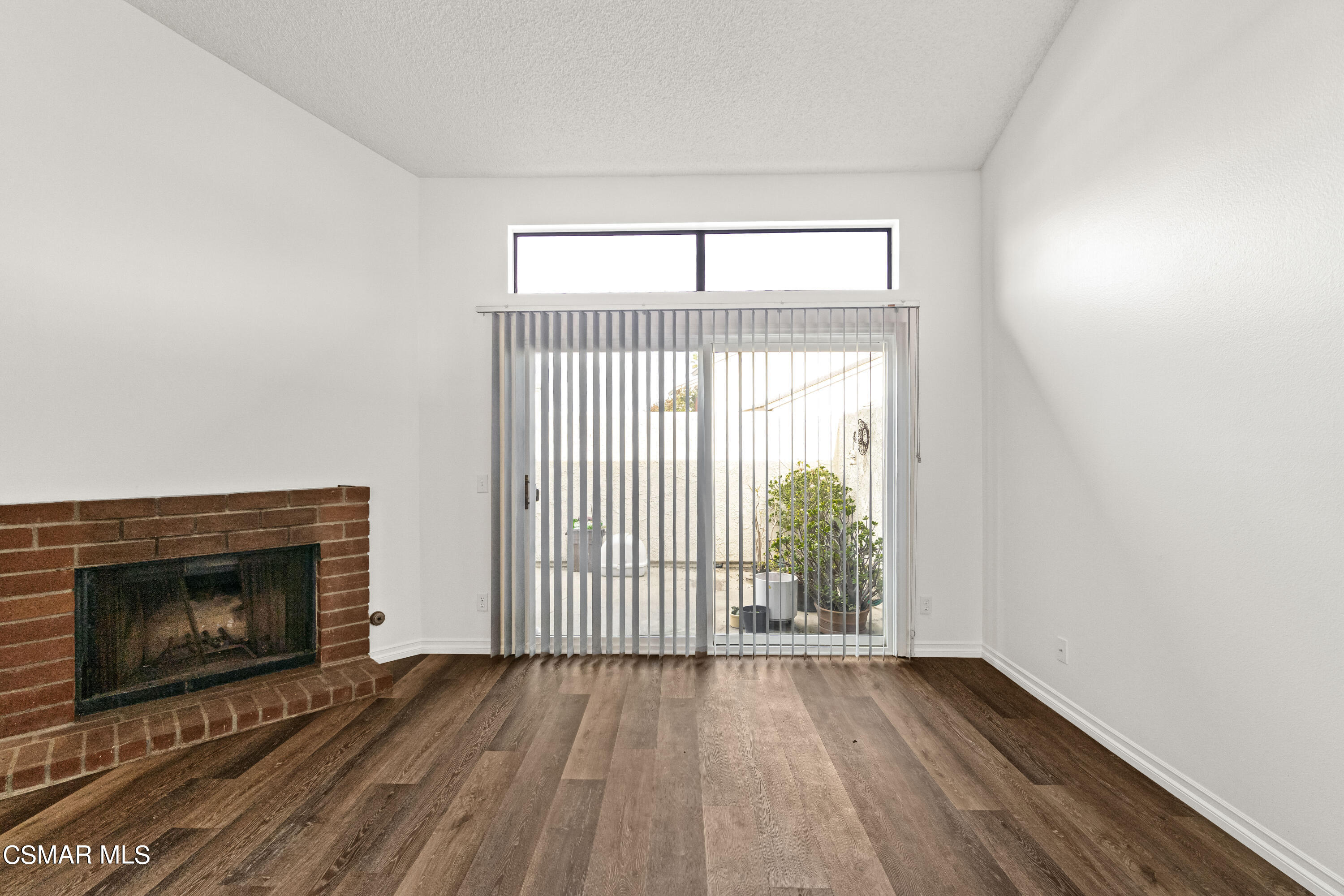 5133 Perkins Road Oxnard, CA 93033 - Photo 11 of 30 an empty room with wooden floor fireplace and windows