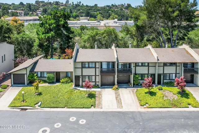 an aerial view of a house with swimming pool and large trees
