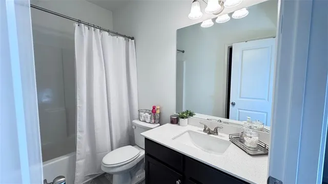 a bathroom with a sink a toilet a mirror and shower curtain